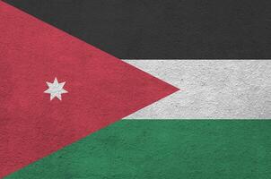 Jordan flag depicted in bright paint colors on old relief plastering wall. Textured banner on rough background photo