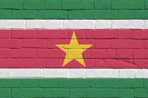 Suriname flag depicted in paint colors on old brick wall. Textured banner on big brick wall masonry background photo