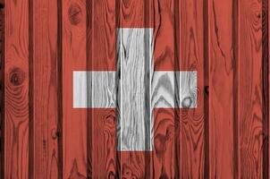 Suiza bandera representado en brillante pintar colores en antiguo de madera pared. texturizado bandera en áspero antecedentes foto