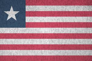 Liberia flag depicted in bright paint colors on old relief plastering wall. Textured banner on rough background photo