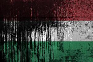 Hungary flag depicted in paint colors on old and dirty oil barrel wall closeup. Textured banner on rough background photo