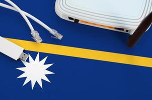 Nauru flag depicted on table with internet rj45 cable, wireless usb wifi adapter and router. Internet connection concept photo