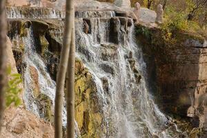 Beautiful waterfall between large rocks in autumn forest. Sofievskiy park in Uman, Ukraine photo
