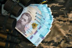 Ukrainian army machine gun belt shells and bunch of hryvnia bills on military uniform. Payments to soldiers of the Ukrainian army, salaries to the military photo