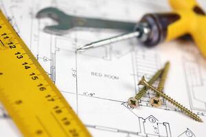 Spanner, screws and other repair tools on blueprints of residential house plan. Restoring, repair, service maintenance cost photo