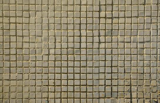 The texture of the old concrete wall, with a coating of shallow tiles of square shape, painted in gray. Background image of a wall of many square white tiles photo