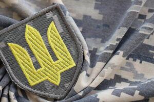 símbolo de ucranio Ejército en el camuflaje uniforme de un ucranio soldado. el concepto de guerra en Ucrania, patriotismo y proteger tu país desde ocupantes foto
