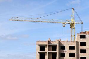 View of a large construction site with buildings under construction and multi-storey residential homes. Tower cranes in action on blue sky background. Housing renovation concept photo