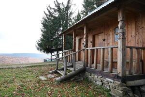 Small wooden house among trees and mountains in the middle of nature on an autumn photo