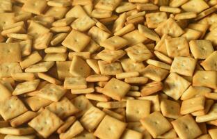 Background texture of small edible squares baked from dough and sprinkled with salt. A lot of salt cracker photo