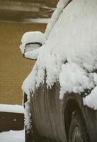 fragmento del coche bajo una capa de nieve después de una fuerte nevada. el cuerpo del coche está cubierto de nieve blanca foto