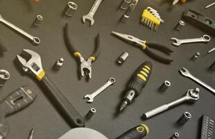 Handyman tool kit on black wooden table. Many wrenches and screwdrivers, pilers and other tools for any types of repair or construction works. Repairman tools photo