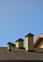 Modern roofing and decoration of chimneys. Flexible bitumen or slate shingles. The absence of corrosion and condensation due to the flexible roof photo