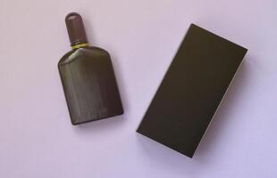 frasco de perfume morado oscuro con cinta dorada sobre fondo de papel pastel. fragancia de moda foto