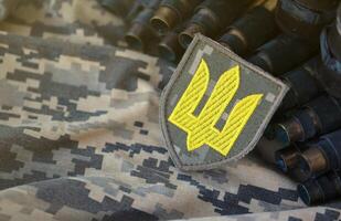 Ukrainian army symbol on machine gun belt lies on ukrainian pixeled military camouflage photo