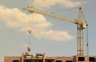 View of a large construction site with buildings under construction and multi-storey residential homes. Tower cranes in action on blue sky background. Housing renovation concept photo