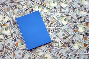 Office workplace table with blank notebook or notepad and many hundred dollar bills photo