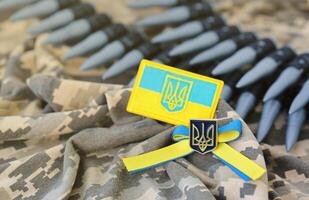 ucranio símbolo y un máquina pistola cinturón en el camuflaje uniforme de un ucranio soldado. el concepto de guerra en Ucrania, patriotismo y proteger tu país desde ocupantes foto