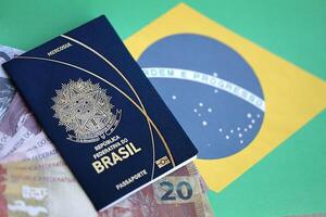 Passport book of Federative Republic of Brazil and brazilian reais money bills on brazil flag background photo