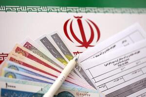 Iranian annual income tax return form F20-25-006 ready to fill on table with pen and iranian money on flag photo