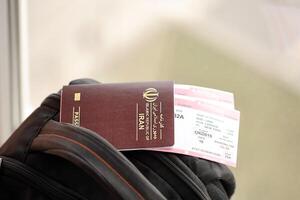Red Islamic Republic of Iran passport with airline tickets on touristic backpack photo