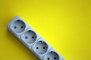 White electrical multi plug extender with european socket on bright yellow background photo