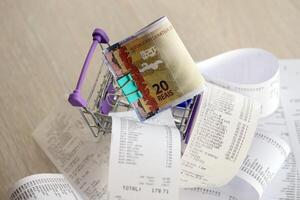 Brazilian reais money bills bunch in shopping trolley surrounded by many paper receipts photo