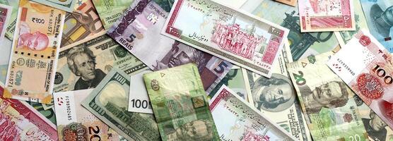 Many banknotes of different currency. Background of big amount of random money bills photo