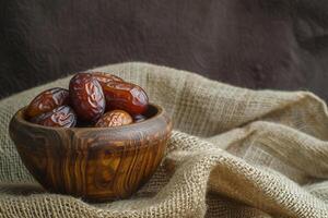 AI generated Gleaming Dates in a Carved Wooden Bowl on Burlap Cloth photo