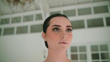 Portrait of a young woman with a serene expression, indoors with soft lighting and a minimalist background. video