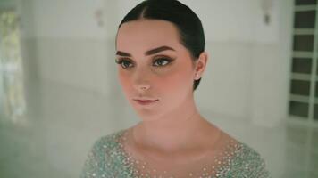 Portrait of a young woman with a serene expression, standing indoors with soft lighting and a blurred background. video