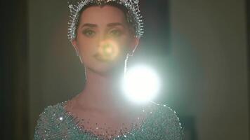 Portrait of a woman with sparkling tiara, back lit by a soft glow, creating a mystical and elegant atmosphere. video