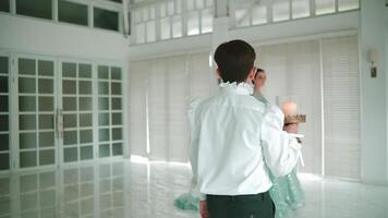 Elegant couple dancing in a bright, modern room with large windows and minimalist decor. video