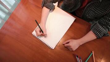 Overhead view of a person sketching on a white pad with a pencil, creativity and art concept, with copy space. video