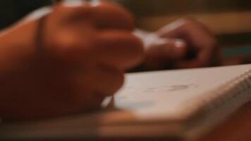 Blurred image of a person sketching on paper, focus on hand with pencil, artistic concept. video