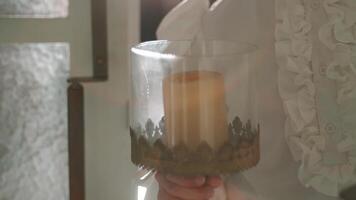 Close-up of a person in a white blouse pouring a beverage into a glass with soft lighting and a blurred background. video