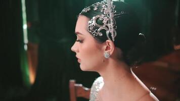 Elegant woman with a decorative headpiece looking away thoughtfully, with soft lighting and a dark background. video