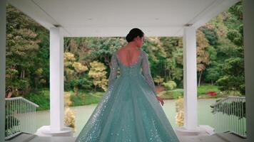 Woman in elegant dress standing on porch overlooking garden. video