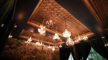 Elegant chandeliers hanging from a decorative ceiling in a vintage room with ambient lighting. video