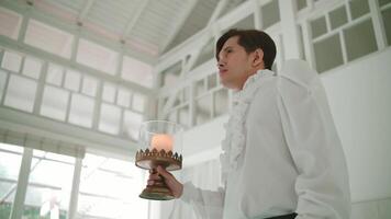 Person dressed as an angel holding a candle lantern in a bright room, conveying a sense of guidance or hope. video