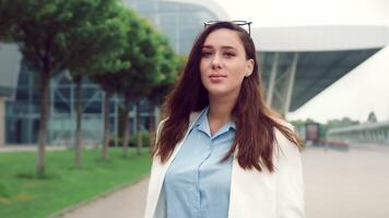 portret van een mooi Kaukasisch vrouw met zwart haar- glimlachen en op zoek Bij de camera. meisje Aan de straat Aan een achtergrond van modern interieurs glimlachen Bij de camera. video