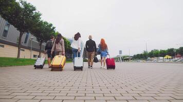 cinq en voyageant copains tête à le aéroport Terminal avec bagage dans main. touristes et les voyageurs aller sur une périple avec bagage. video