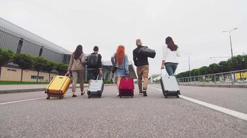 cinque in viaggio amici testa per il aeroporto terminale con bagaglio nel mano. turisti e i viaggiatori partire su un' viaggio con bagaglio. video