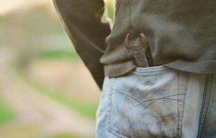 Spanner in the jeans pocket of a mechanic outdoors. The concept of repairing a car or equipment with his own hands in the open air photo