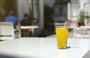 vaso de naranja jugo con el plastico Paja en blanco mesa en restaurante al aire libre salón zona foto