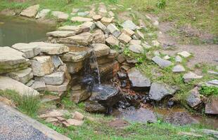 Close up of a small waterfall spilling over moss covered rocks in regional park. Handmade river waterfall photo