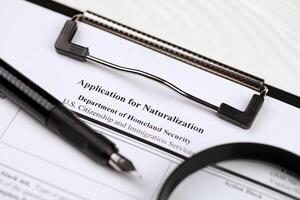 N-400 Application for Naturalization blank form on A4 tablet lies on office table with pen and magnifying glass photo