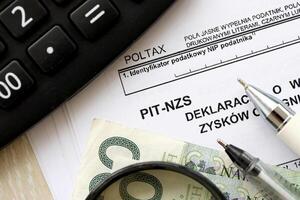 Declaration of income amount from unrealized profits obtained by enterprise as inheritance, PIT-NZS form on accountant table with pen and polish zloty money bills photo