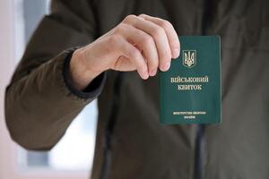 Young ukrainian conscript soldier shows his military token or army ID ticket indoors photo