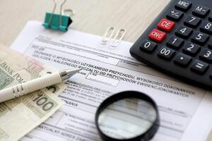 Declaration of amount of income obtained, amount of deductions made and lump sum due from recorded income, PIT-28 form on accountant table with pen and polish zloty money bills photo